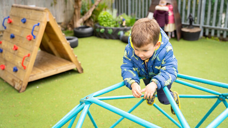 Sunrise Day Nursery - A boy playing on our frame in the playground